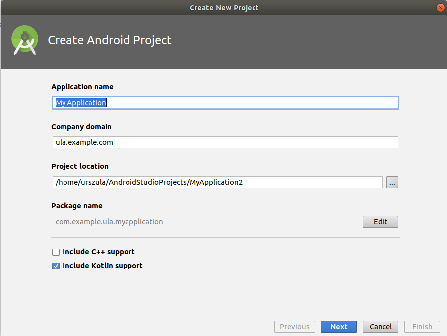 Ekran 'Create Android Project' z polami 'Application name' (uzupełnione domyślnie tekstem 'My Application'), 'Company domain' (uzupełnione tekstem: 'ula.example.com'), 'Project location' (uzupełniony domyślną ścieżką),'Package name' i poniżej wpisane na szaro 'com.example.ula.myapplication'. Poniżej niezaznaczony checkbox 'Include C++ support' i zaznaczony checkbox 'Include Kotlin support'. Na dole przyciski Previous (nieaktywny), Next, Cancel, Finish (nieaktywny).